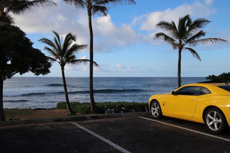 Camaro Horsepower - a yellow sports car parked in a parking lot next to the ocean