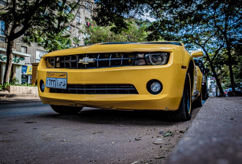 Camaro Deals - a yellow sports car parked on the side of the road