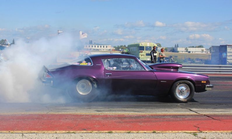 Camaro Drag Racing - purple coupe burning out on road during daytime